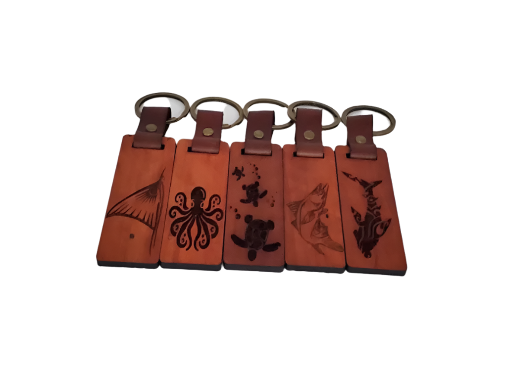 Five brown leather keychains with engraved designs on a white background