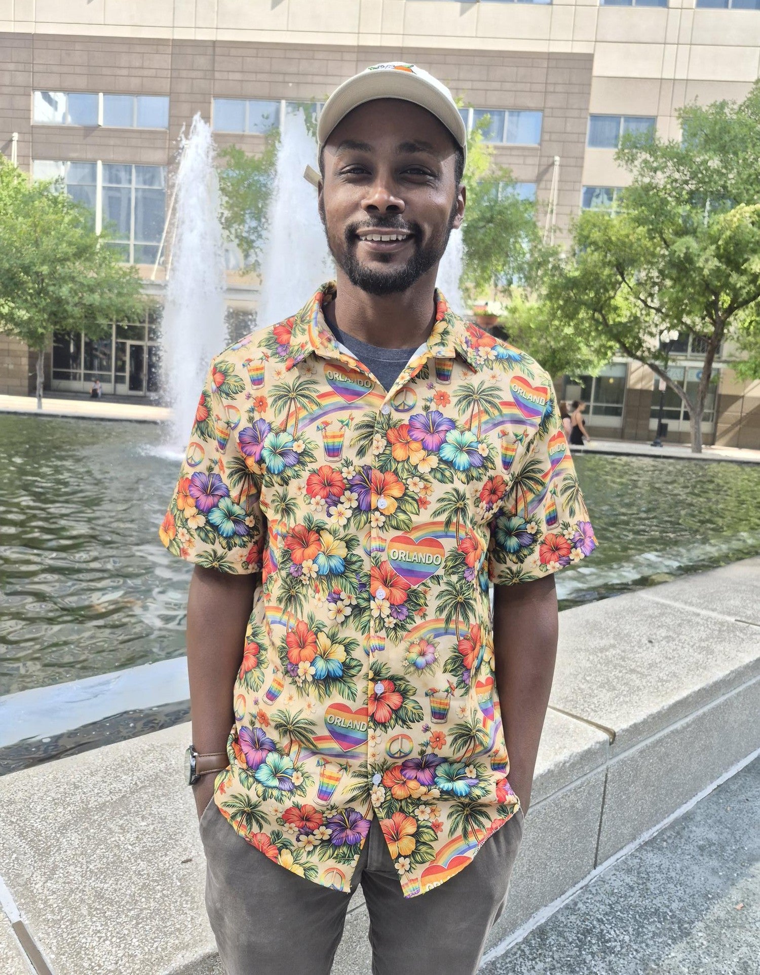 Man wearing a colorful floral shirt standing in front of a fountain.
