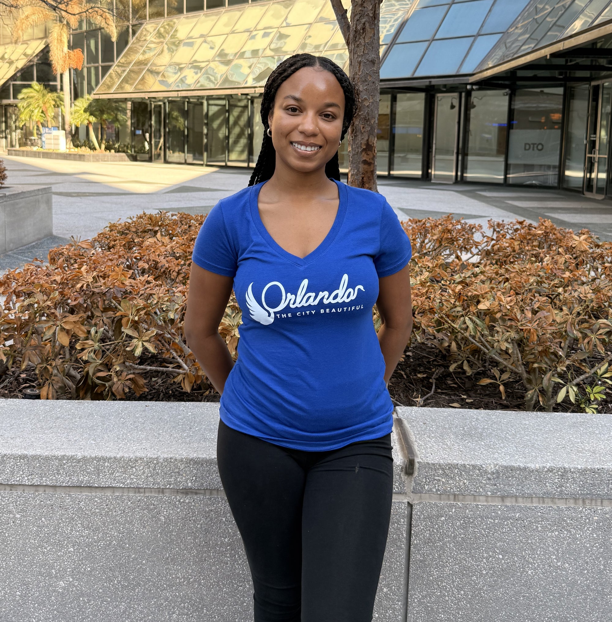 Woman wearing a blue 'Orlando' t-shirt standing outdoors in front of a building.