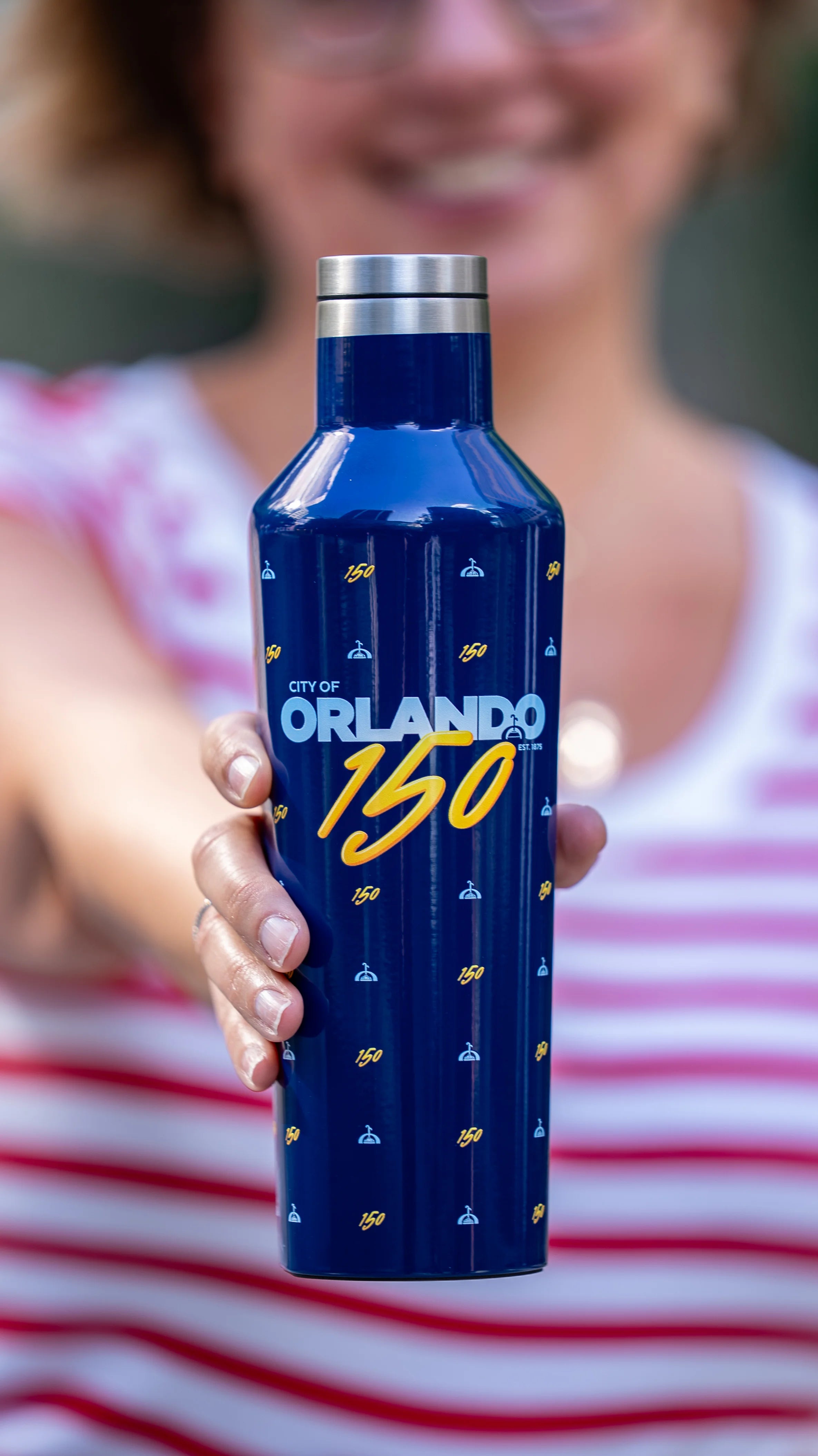 Person holding a blue water bottle with 'City of Orlando 150' text