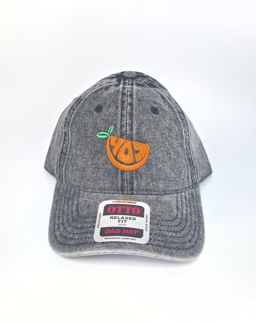 A washed gray denim baseball cap featuring an embroidered orange slice with a green leaf on the front. The brim has a white '99.