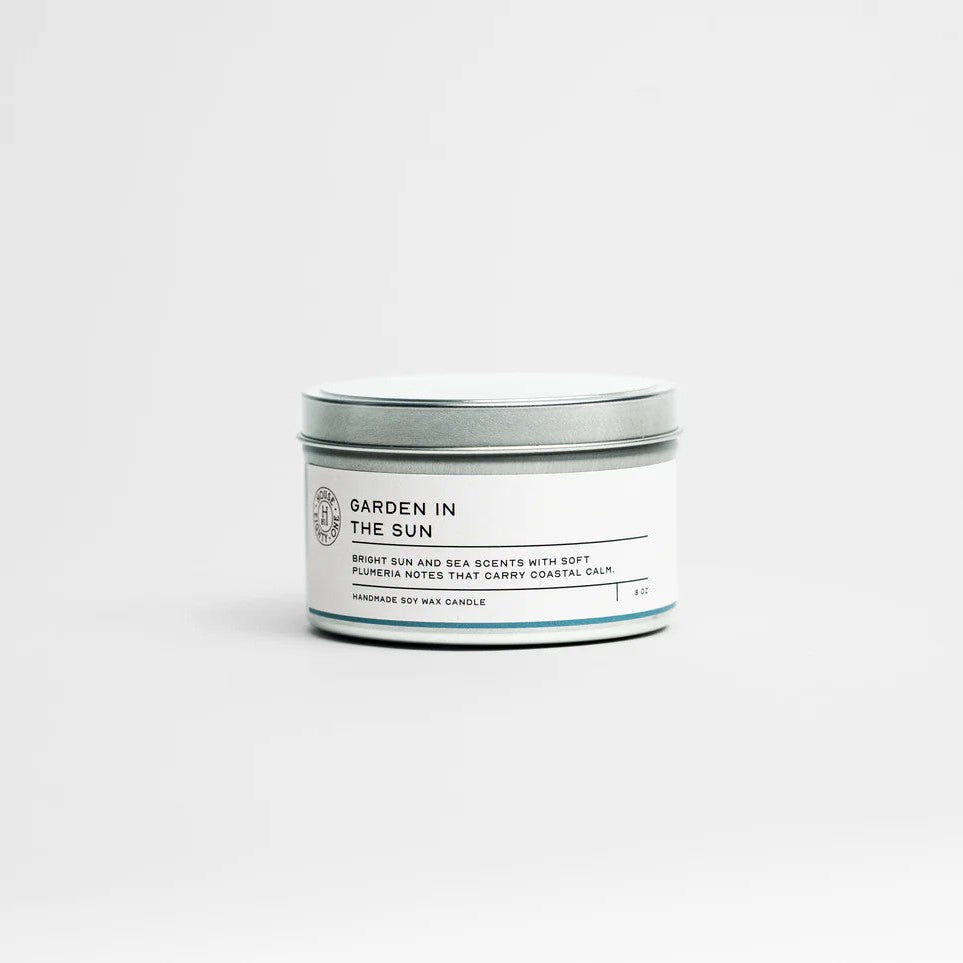 Candle in a tin labeled 'Garden in the Sun' on a white background